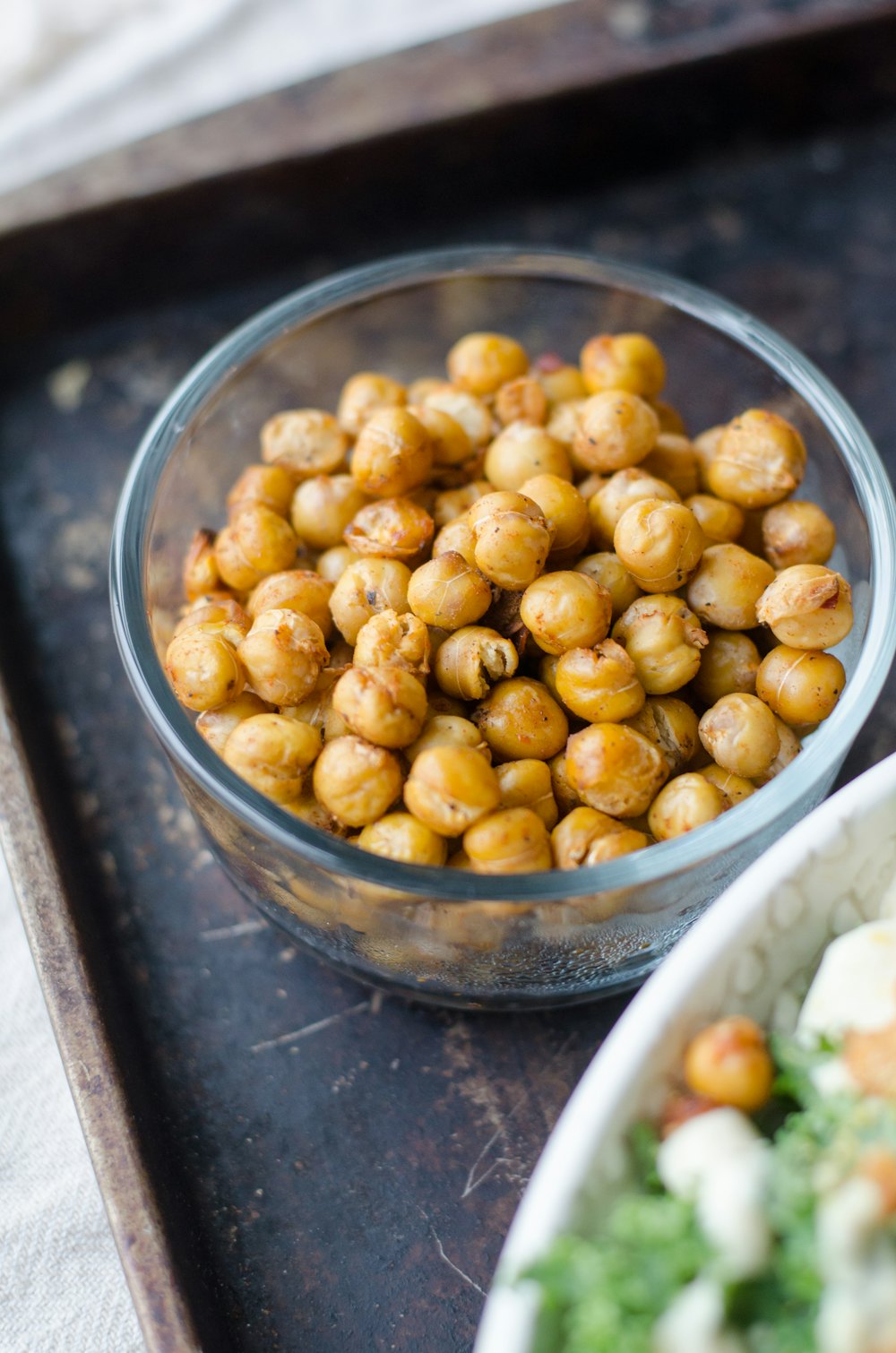A glass bowl of dried chickpeas on a dark tray